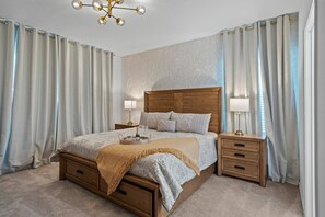 Ein Schlafzimmer mit einem hölzernen Bett, zwei Nachttischen, einer Chandelüster und Vorhängen.
