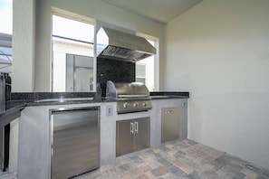 A kitchen with a stainless steel range, a built-in oven, and a dishwasher. - 9BR Solara Home Pool, spa & Themed Rooms (Kissimmee)