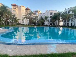 Ein Swimmingpool, umgeben von Palmen und modernen Gebäuden.