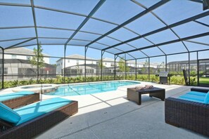 Ein überdachter Außenpool mit Liegestühlen und einer Grillgegend.