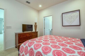 Ein Schlafzimmer mit Bett, Schminktisch, Fernseher und Bildern an der Wand.