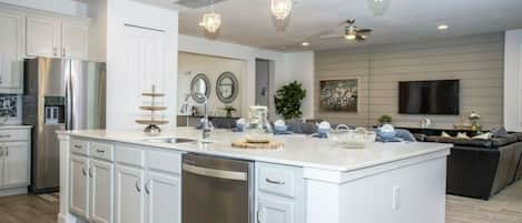 A modern kitchen with a large island, stainless steel appliances, and pendant lighting.
