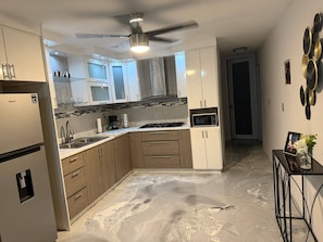 A modern kitchen with a built-in stove, a microwave, and a ceiling fan. - Modern & Cozy Home2 Mins to Airport and car rental (Carolina)