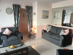 A living room with two sofas, a coffee table with bananas, a lamp, and a clock on the wall. - Beautiful Beach Front Line Apartment, perfect central location. (Fuengirola)