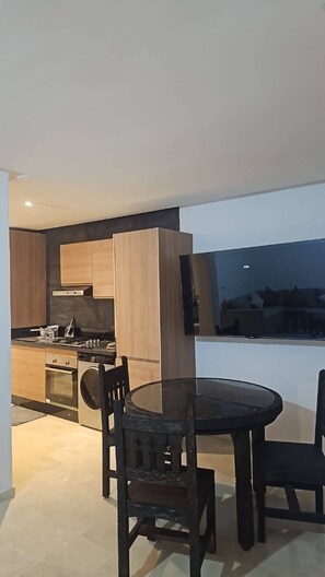 A modern kitchen with a dining area, including a round table and chairs. - Sea View Apt in Taghazout - Pool - Surf & Golf (Agadir)
