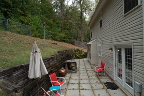 Eine Terrasse mit Sitzgelegenheit im Freien, einem Grill und einem Sonnenschirm.