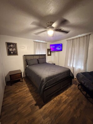 A bedroom with a bed, a ceiling fan, a television, and a nightstand. - Country Living, Just Minutes From the City (Bryan)