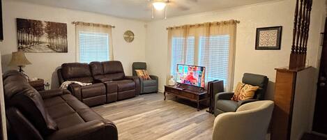 A living room with a sectional sofa, a recliner, a coffee table, and a television.