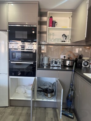 A modern kitchen with a Bosch oven, a microwave, a coffee maker, and a vacuum cleaner. - Perfect 3-bedroom house in tranquil Wembley for your getaway (Wembley)