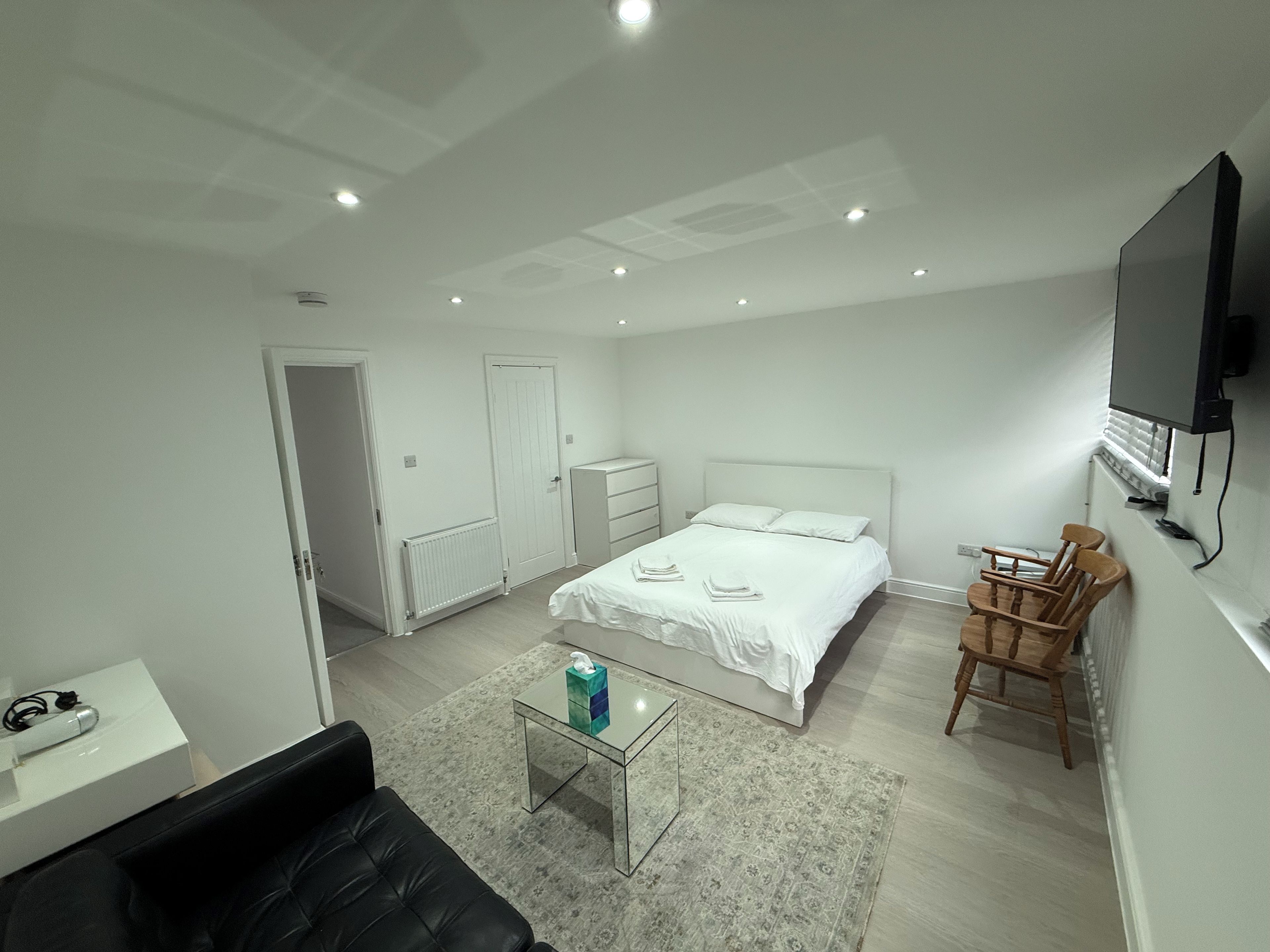 A modern bedroom with a bed, a desk, a chair, and a television.