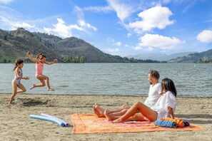 Escena de playa con un lago, montañas y cielo despejado.