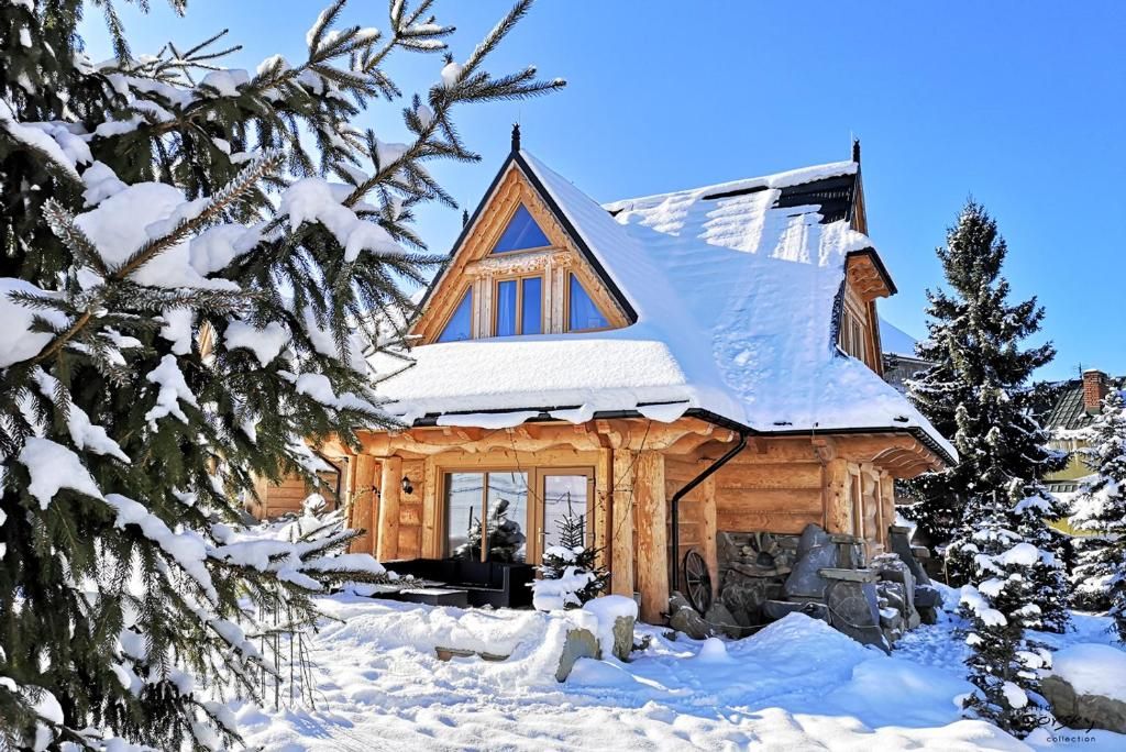 A wooden cabin with a sloped roof, surrounded by snow-covered trees.