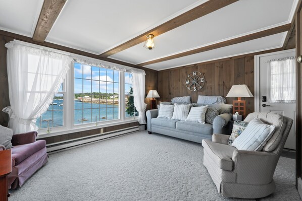 A living room with a view of a body of water, a fireplace, and a large window with curtains.