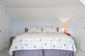 A bedroom with a bed, a nightstand, a lamp, and a door.
