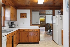 A kitchen with wooden cabinets, a white countertop, a coffee maker, and a refrigerator.
