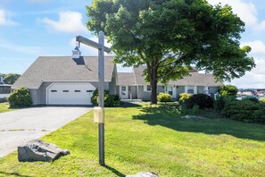 A residential house with a garage, a large tree, and a street lamp.