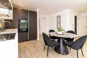 A modern kitchen with dark wood cabinets, a built-in oven, and a stainless steel range hood. - Spacious 2-bed Canal-side Apartment Sleeps 4 (Salford)