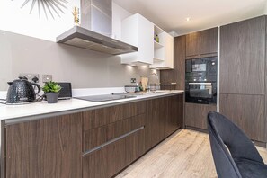 A modern kitchen with a built-in oven, a coffee maker, and a sink. - Spacious 2-bed Canal-side Apartment Sleeps 4 (Salford)