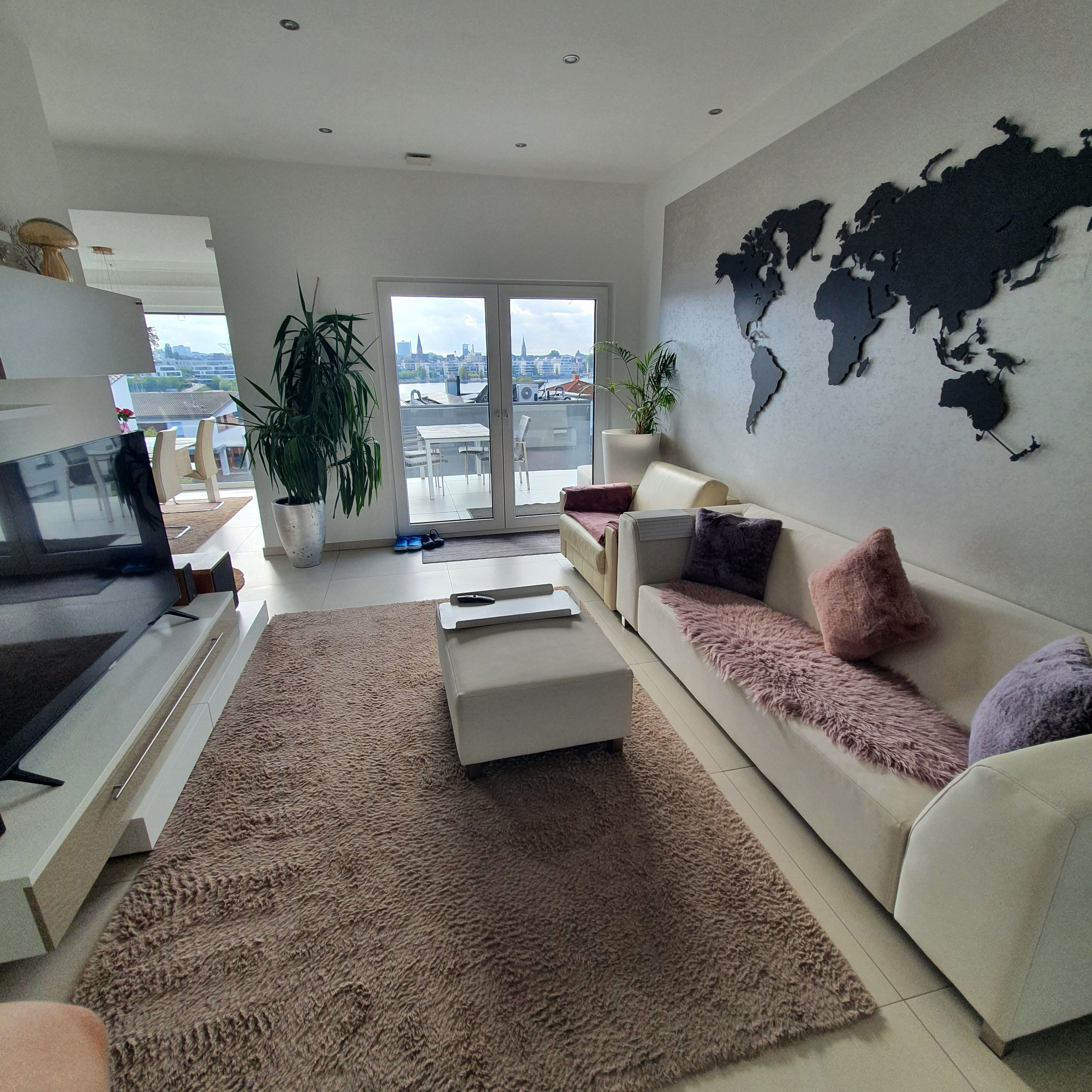 Un salon moderne avec un canapé, une table basse, un téléviseur et une carte du monde accrochée au mur.