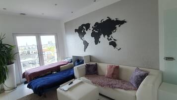 Un salon moderne agrémenté d’une décoration murale représentant une carte du monde, d’un canapé, d’une table basse et d’une grande fenêtre offrant une vue sur les bâtiments.