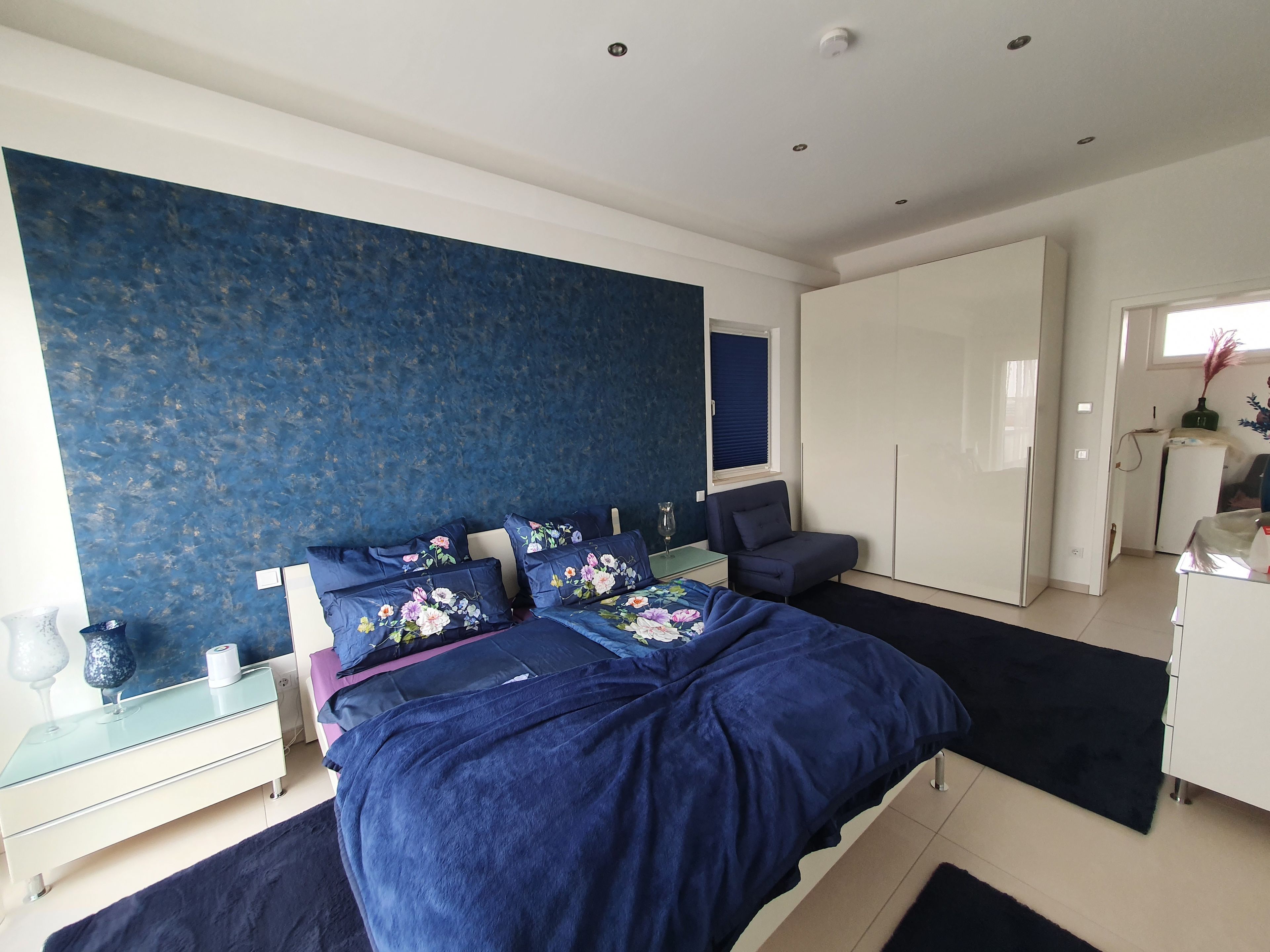 Une chambre à coucher comprenant un lit, une table de chevet, une commode, une chaise et une armoire.