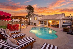 A backyard with a swimming pool, lounge chairs, a barbecue area, and a pergola with string lights. - The Sunny Social | Pool • Hot Tub • Games Galore! (Chandler)