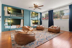A room with bunk beds, bean bags, a patterned rug, and a ceiling fan. - The Sunny Social | Pool • Hot Tub • Games Galore! (Chandler)