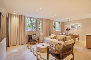 Ein modernes Wohnzimmer mit einer Couch, Sesseln, einem Couchtisch und einem Essbereich mit Tisch und Stühlen.