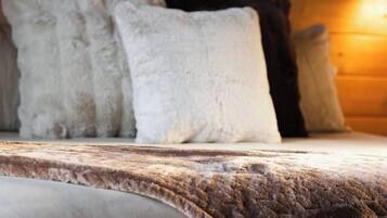 A bed with a textured blanket and pillows, a wooden headboard, and a wall-mounted light fixture.