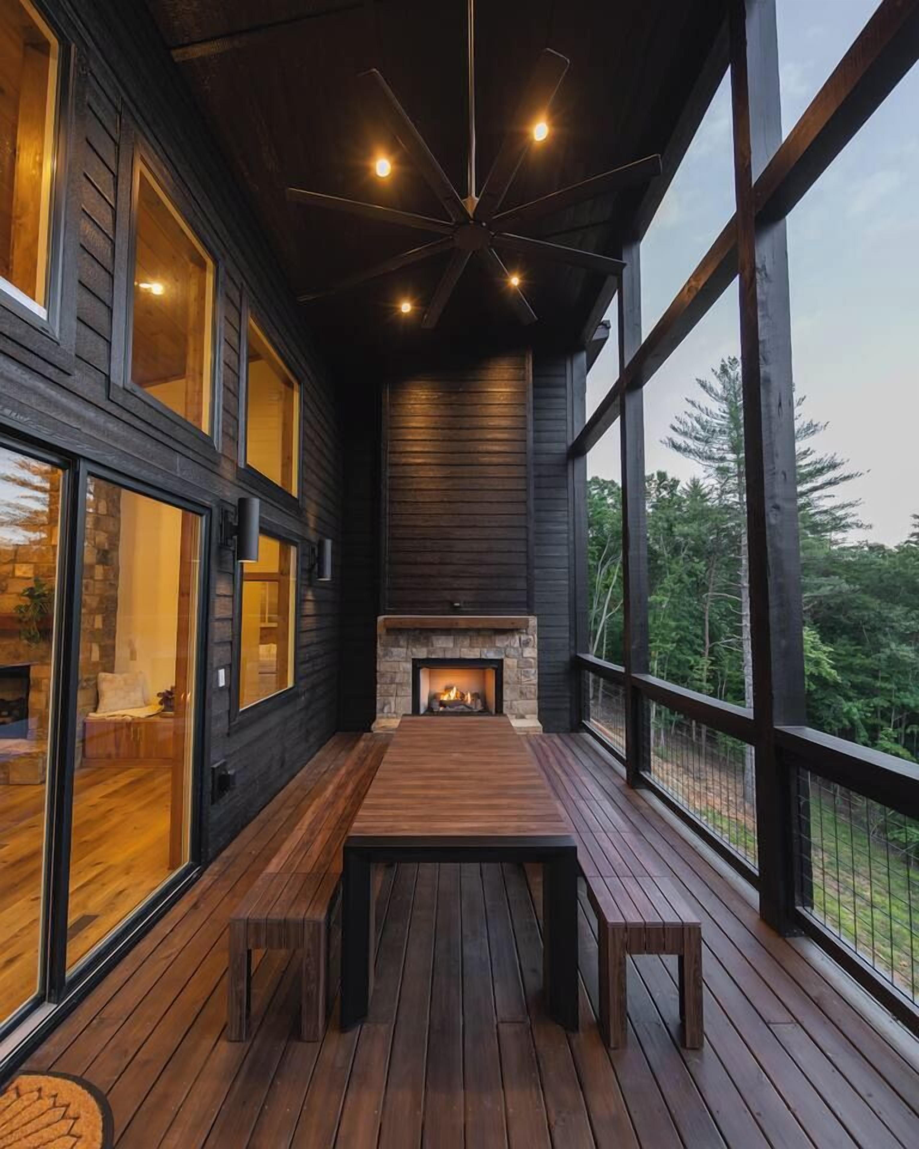 A modern interior with a fireplace, wooden deck, and large windows.