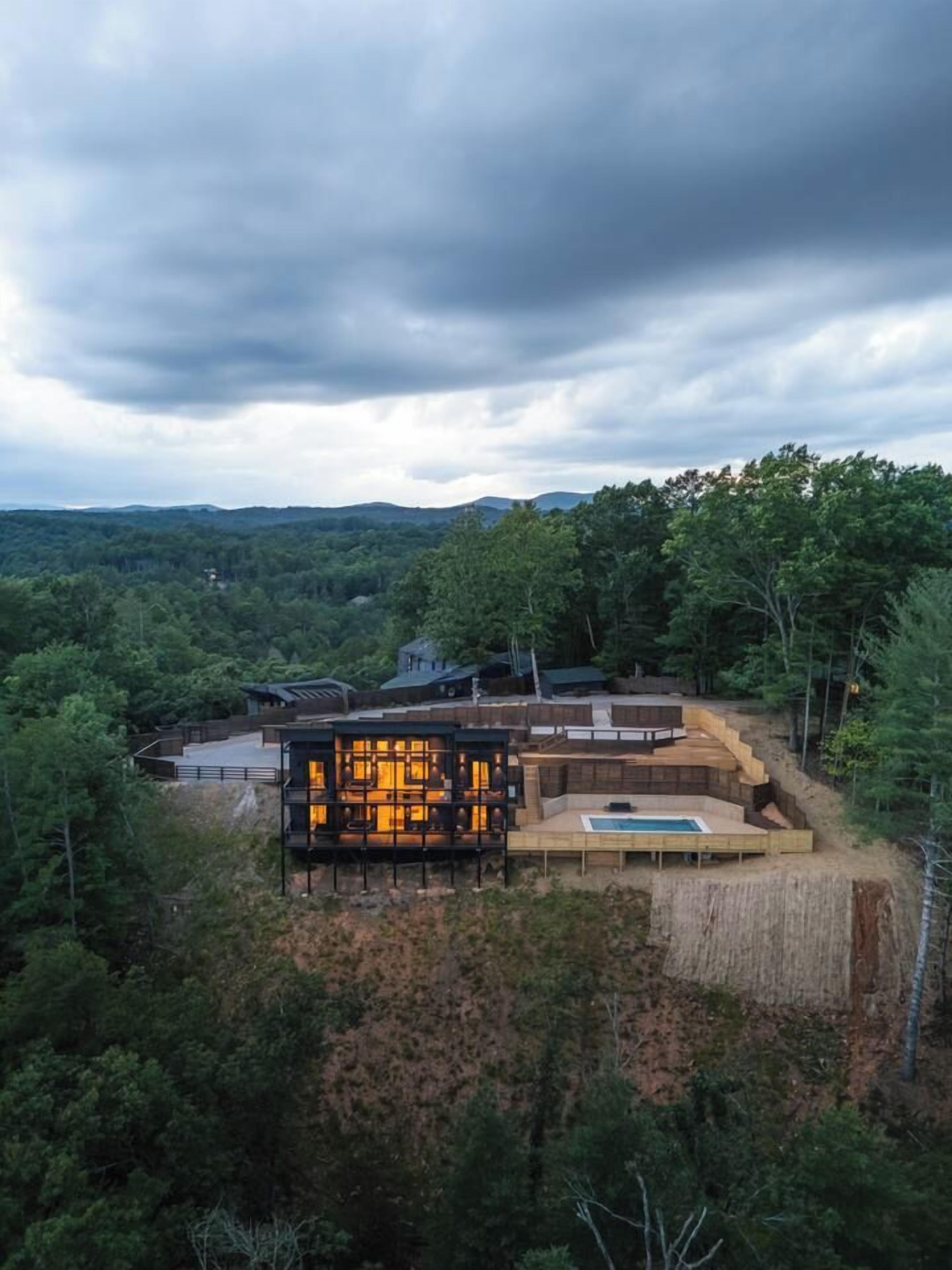 A modern house with a pool, surrounded by dense forest.