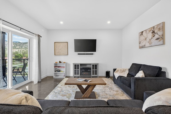 A modern living room with a fireplace, a flat-screen TV, and a sofa.