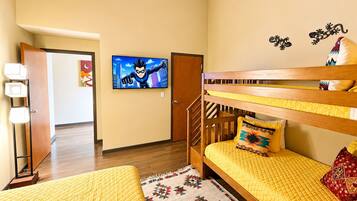 A room with a bunk bed, a television, a door, and a patterned rug.