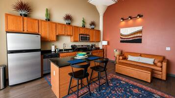 Una cocina moderna con armarios de madera, un refrigerador de acero inoxidable y una isla central con taburetes de bar.