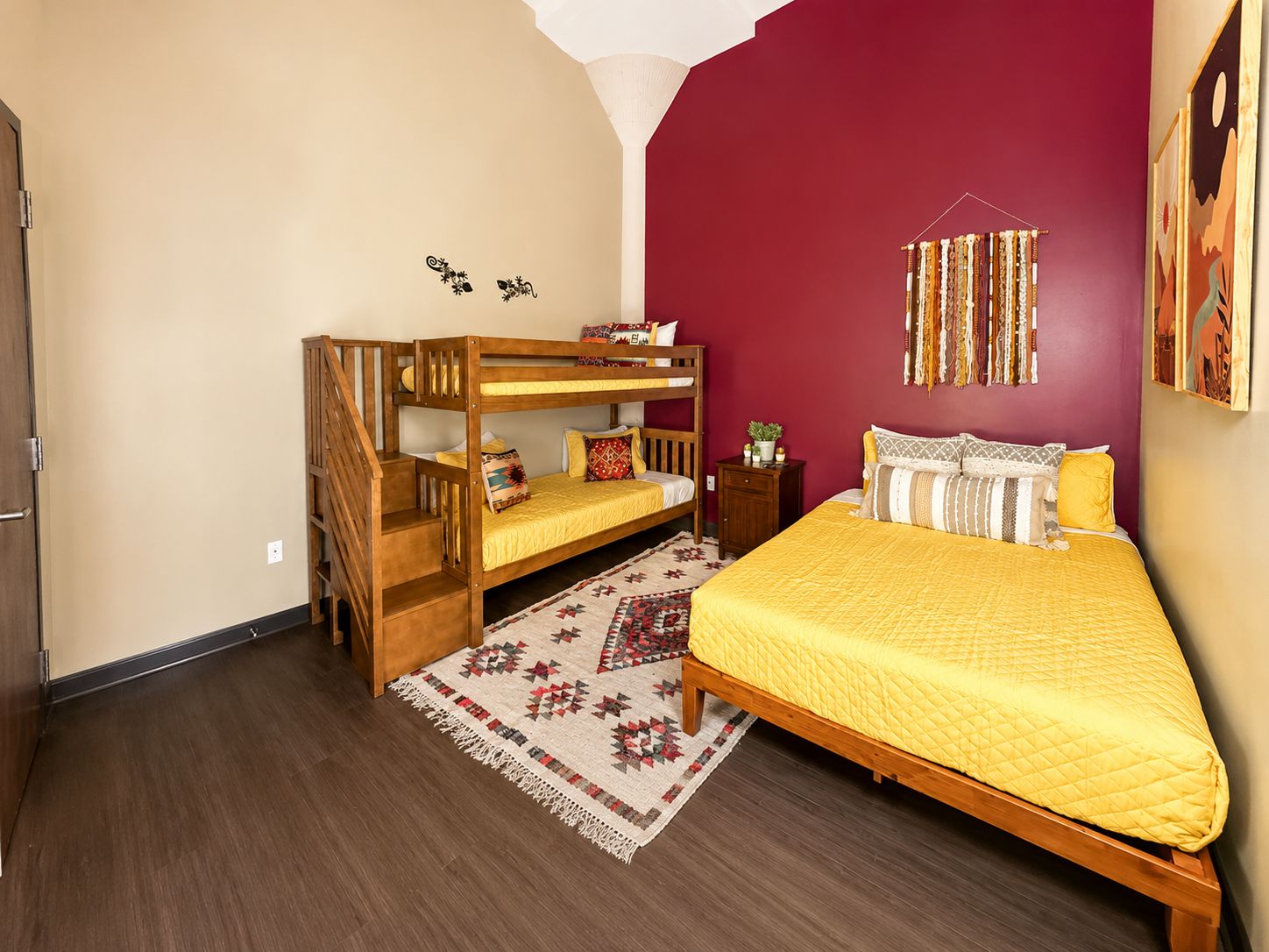Een slaapkamer met een stapelbed, een enkel bed, een kamerbreed tapijt met dessin, en een muur met decoratieve accessoires.