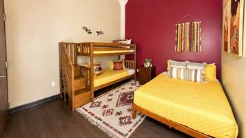 Een slaapkamer met een stapelbed, een enkel bed, een kamerbreed tapijt met dessin, en een muur met decoratieve accessoires.