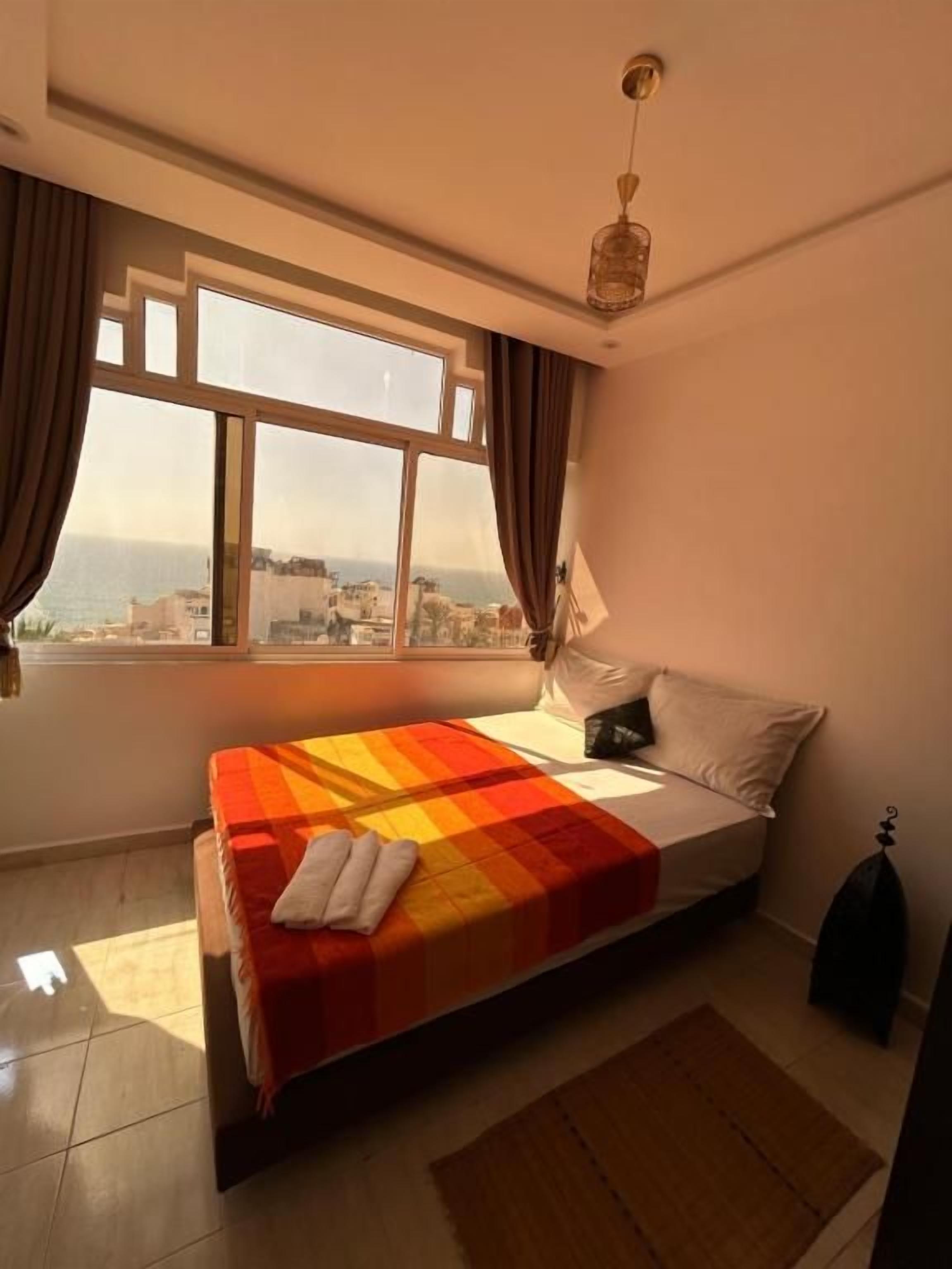 Un dormitorio con una cama, un ventanal y vistas a edificios.