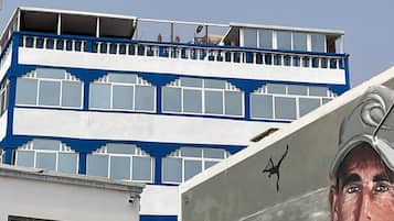 A building with a blue and white facade, a mural with a person, and a fence.