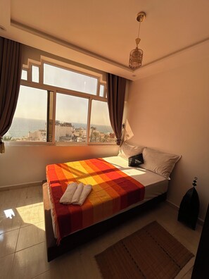 A bedroom with a bed, a view of the sea, and a window.