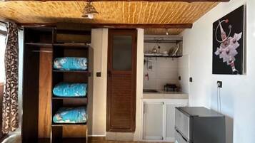 Una habitación con dos camas, un kitchenette y techo de madera.
