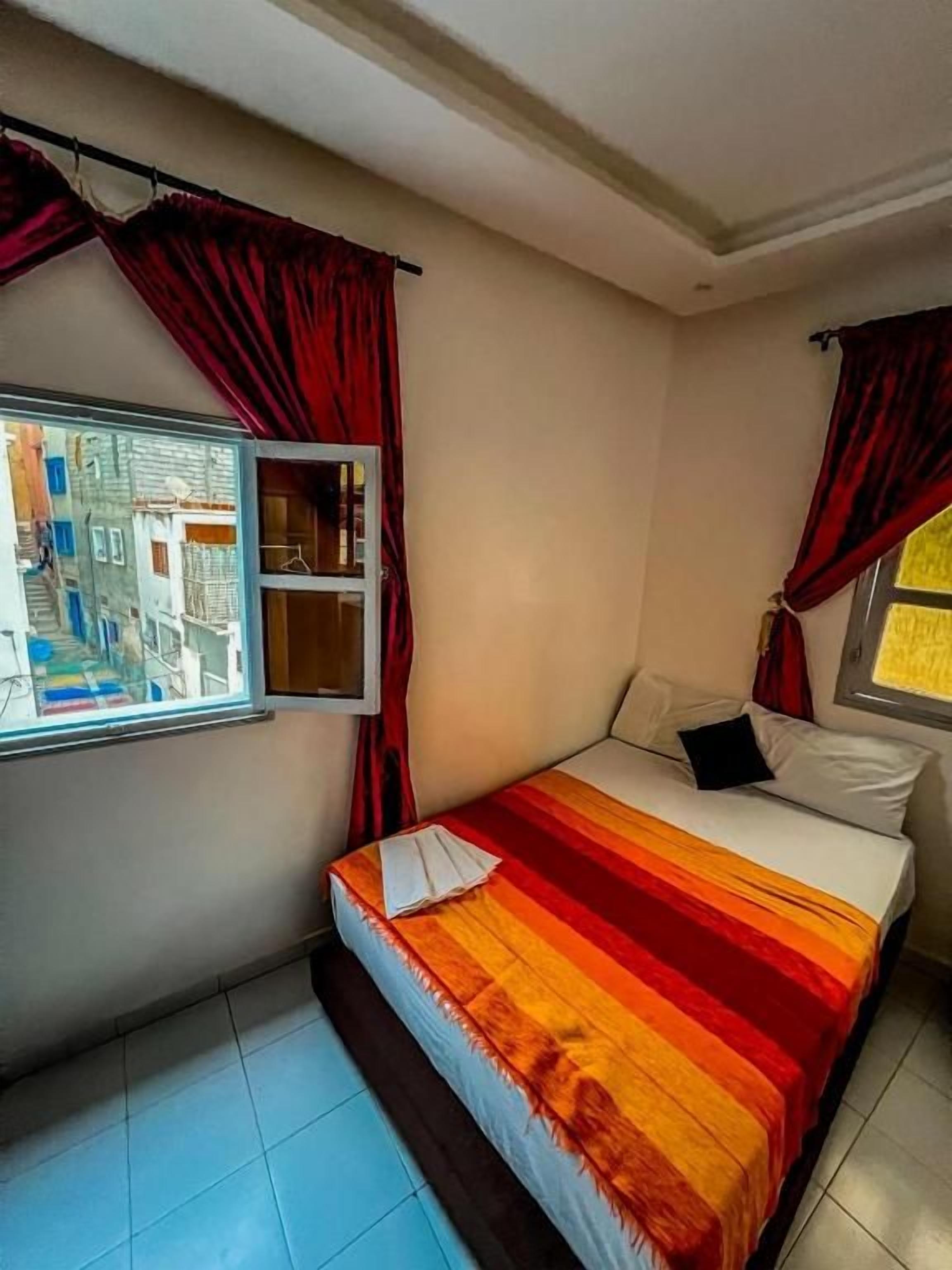 Une chambre à coucher avec un lit, des rideaux et une fenêtre.