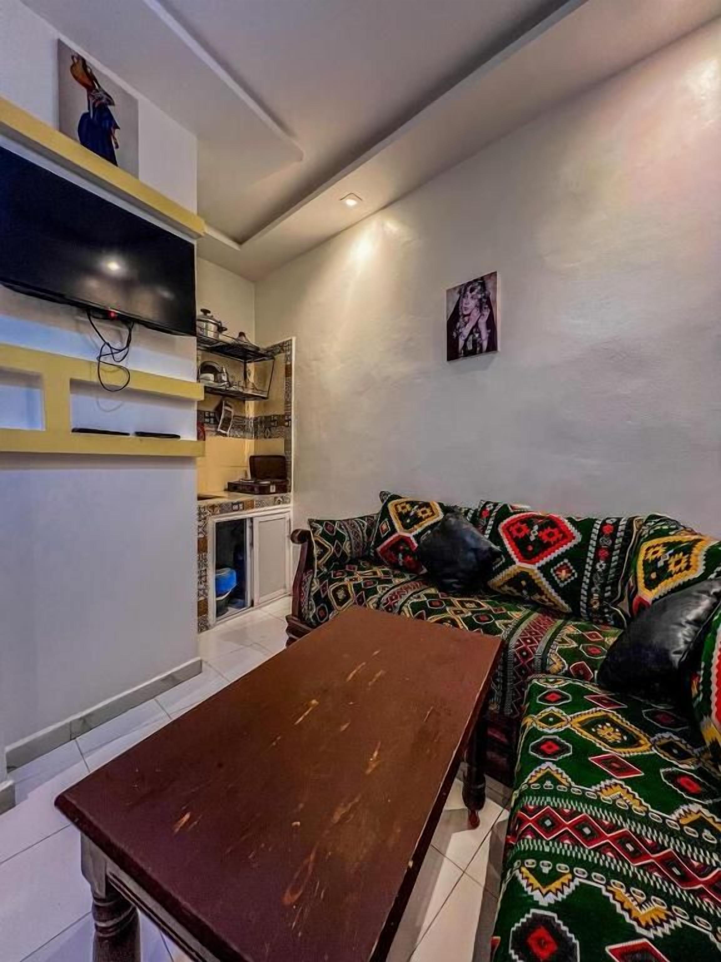 Una sala de estar con un sofá, una mesa de centro y un televisor montado en la pared.