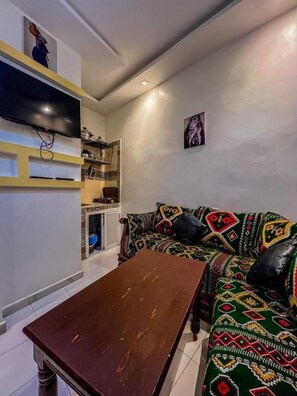 Ein Wohnzimmer mit einer Couch, einem Couchtisch und einem an der Wand befestigten Fernseher.