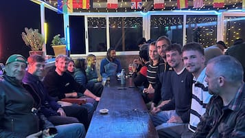 Un grupo de personas sentadas alrededor de una mesa de madera en una habitación con ventanas y banderas.