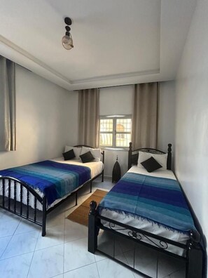 Ein Schlafzimmer mit zwei Einzelbetten, einem Fenster und einer Deckenleuchte.
