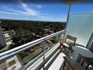 En balkong med utsikt över ett bostadsområde, ett bord och två stolar.