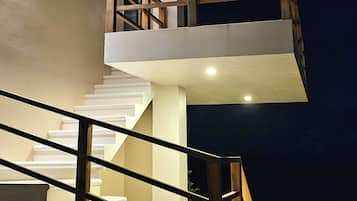 Un escalier extérieur à plusieurs niveaux, doté d’une rambarde en bois, d’un ventilateur de plafond et d’un luminaire.