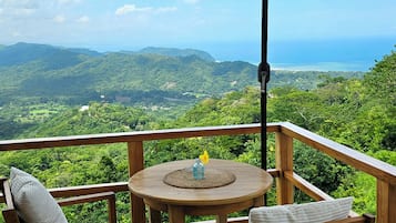 Une terrasse en bois avec une table et des chaises, un parasol et une vue sur un paysage montagneux.