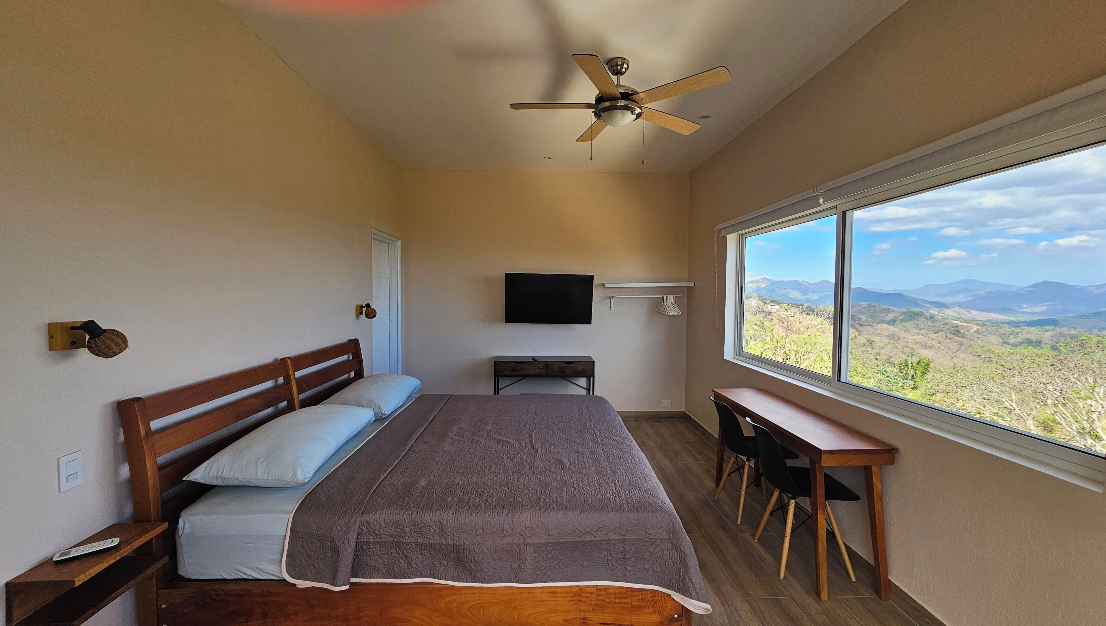 Une chambre à coucher comprenant un lit, un bureau, une télévision et une fenêtre donnant sur la montagne.