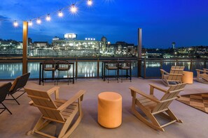 A rooftop terrace with seating and a view of a cityscape at night. - Riverfront Knoxville Suite - Neyland Stadium Views - Pool + Parking (Knoxville)